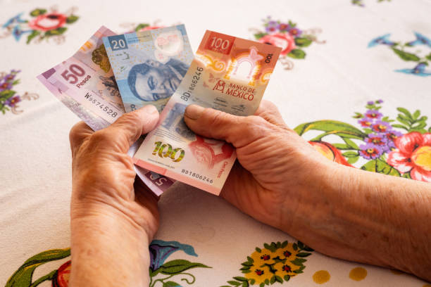 Mexico money, Eldelry woman holds several mexican pesos banknotes in her hand, Financial problems of pensioners, low pensions, high prices